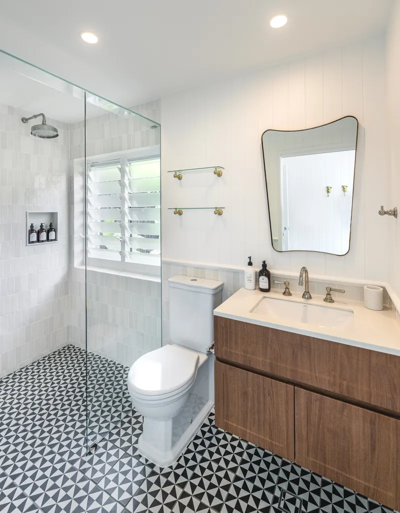 Full bathroom with geometric black-and-white floor tiles, glass shower, timber vanity, and louvre windows at Havana, Port Douglas
