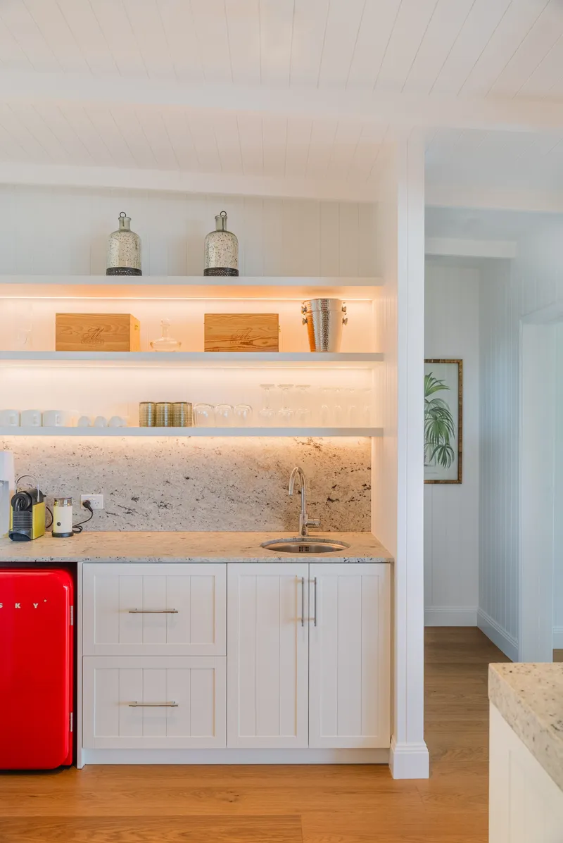 Butler's pantry and wet bar at Havana Port Douglas with marble splashback, open shelving with glassware, LED strip lighting, and retro red mini fridge