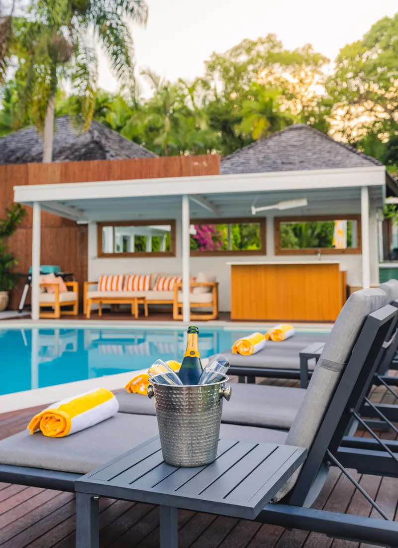 Champagne in an ice bucket on a sun lounger beside the pool at Havana Port Douglas with the covered cabana in the background