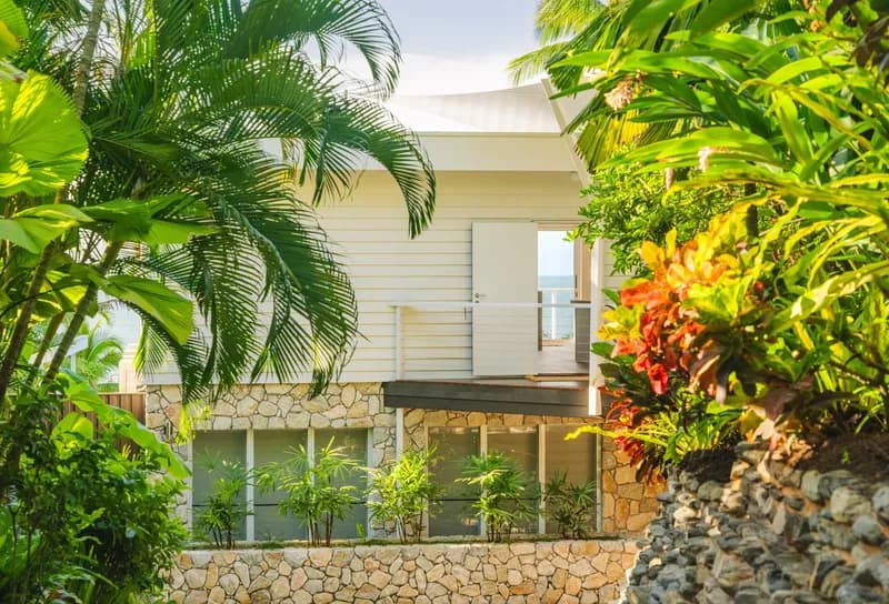 Exterior view of Havana Port Douglas showing the white weatherboard facade with stone base surrounded by tropical gardens