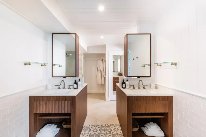 His-and-hers timber vanities with rectangular mirrors and brass fixtures in a white ensuite bathroom at Havana Port Douglas