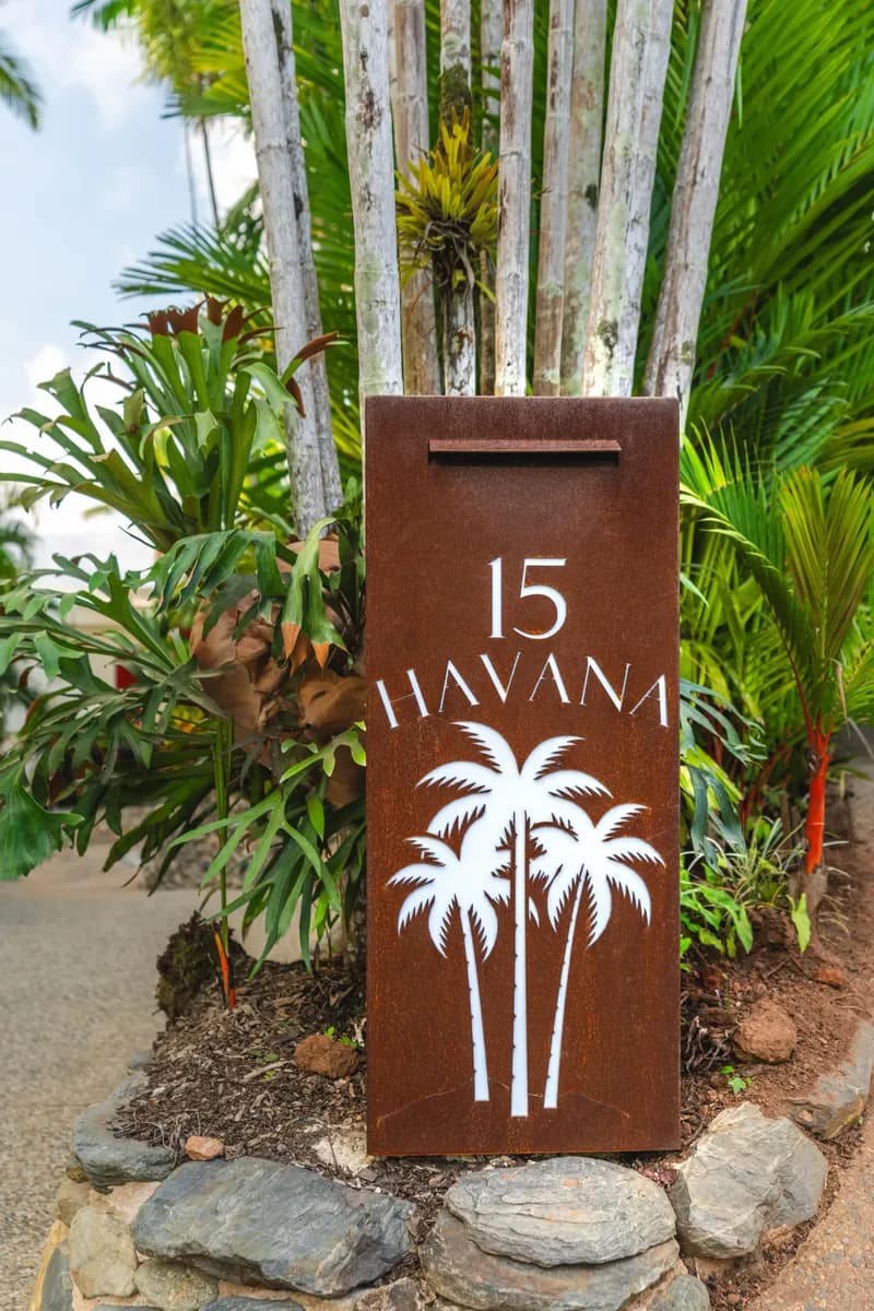 Custom corten steel letterbox with laser-cut '15 Havana' branding and palm tree motif surrounded by tropical plants at the entrance to Havana, 15 Wharf Street, Port Douglas