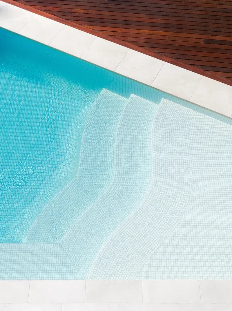Overhead view of curved mosaic-tiled pool steps meeting a timber deck at Havana, Port Douglas