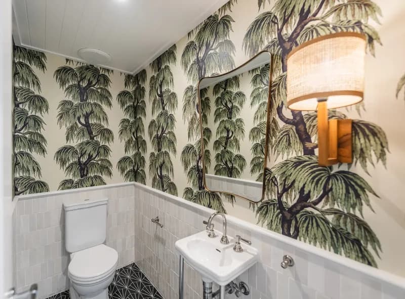 Stylish powder room featuring tropical palm wallpaper, tiled wainscoting, and rattan wall sconce at Havana, Port Douglas