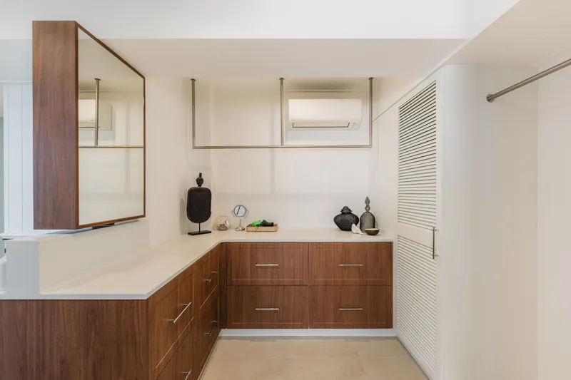 Spacious walk-in robe with warm timber cabinetry, mirror, and decorative accents at Havana, Port Douglas
